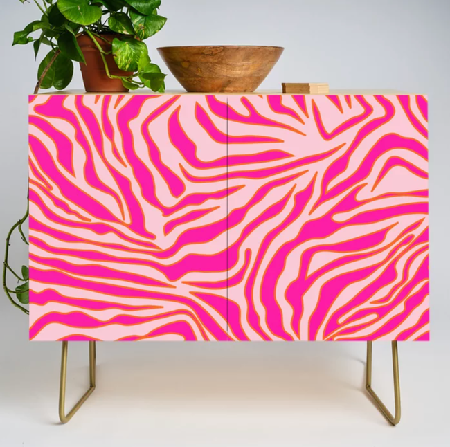 Pink and gold zebra-print bar cabinet featuring sleek gold legs