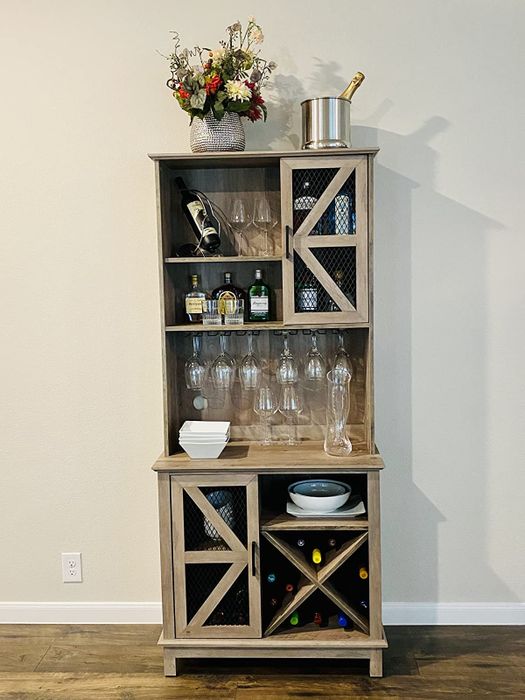 Reviewer image of a tall light wood bar cabinet with bottles and glasses neatly arranged on its shelves