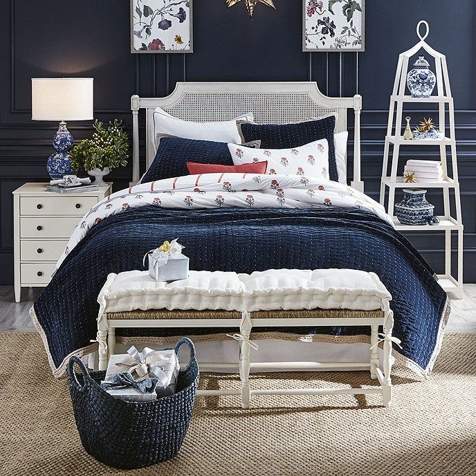the white bench with matching white cushions at the foot of the bed