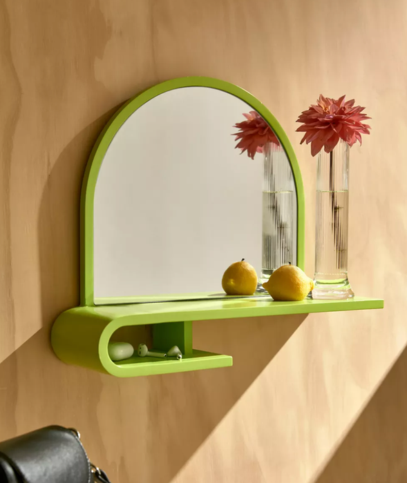 The lime green Maura entryway mirror shelf mounted on a wall