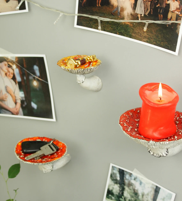 Three mushroom-shaped shelves, each holding candles and keys