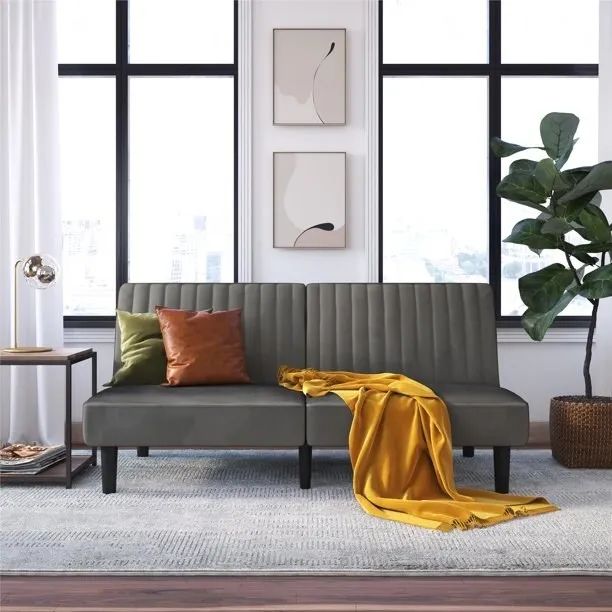 A gray velvet couch adorned with cozy throw pillows and a soft blanket draped over it