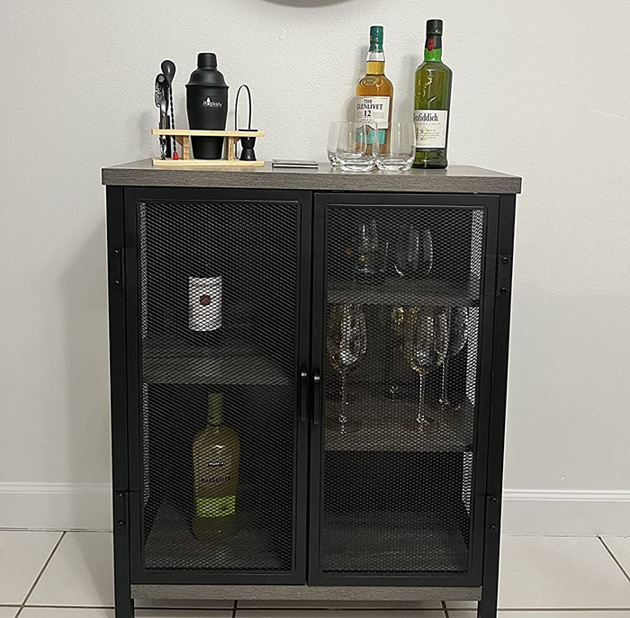Reviewer image of a black metal bar cabinet with mesh doors, housing bottles and wine glasses