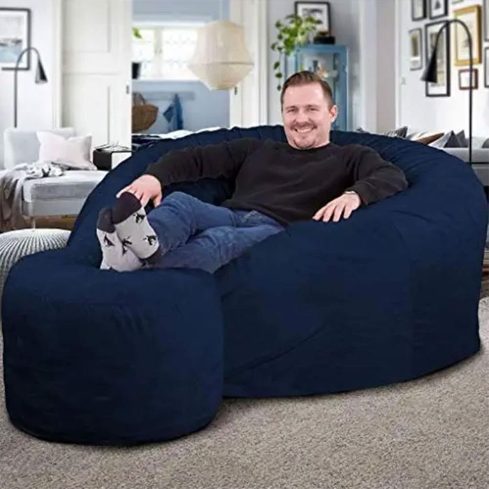 A person unwinds on a large, comfy beanbag chair, lounging in a cozy living room, highlighting the ideal furniture for relaxation.