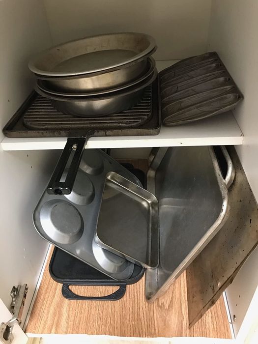 A reviewer's disorganized cabinet before using a pots and pans holder.
