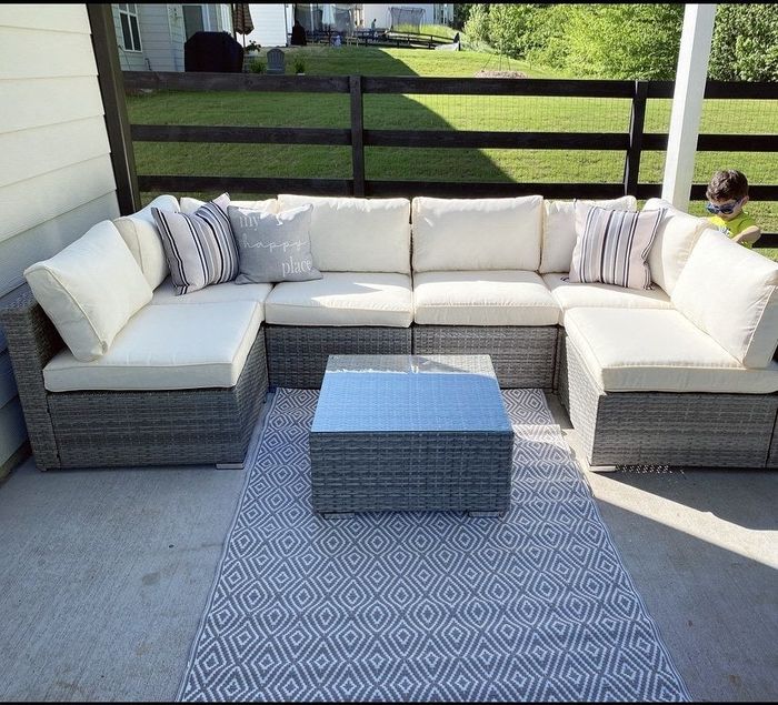 Reviewer photo of a U-shaped configuration with cream-colored cushions surrounding a coffee table on a large deck, with a small boy in the background.