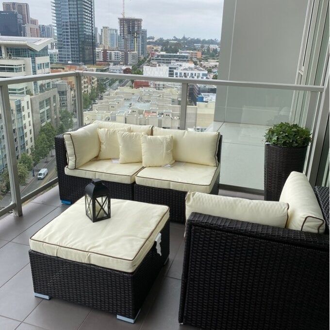 Reviewer photo of a wicker sectional placed on a spacious apartment balcony.