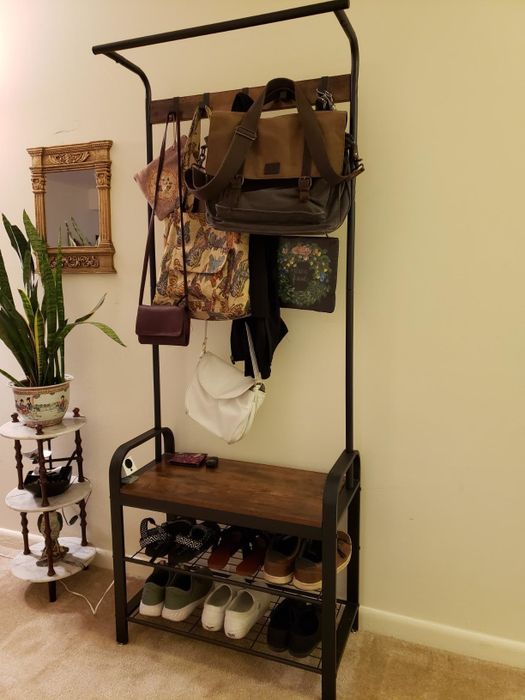 A reviewer's photo showing a coat rack with bags hanging on the hooks and shoes neatly placed on the shelves
