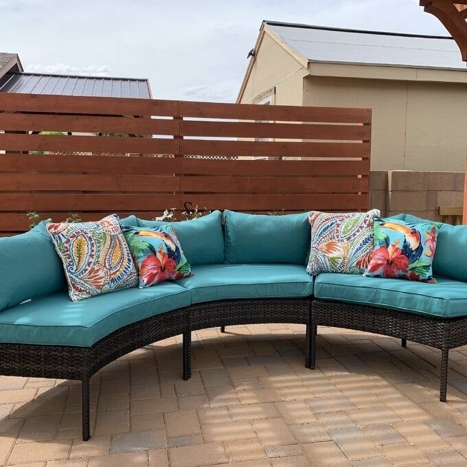 Photo of a curved sectional featuring teal cushions.