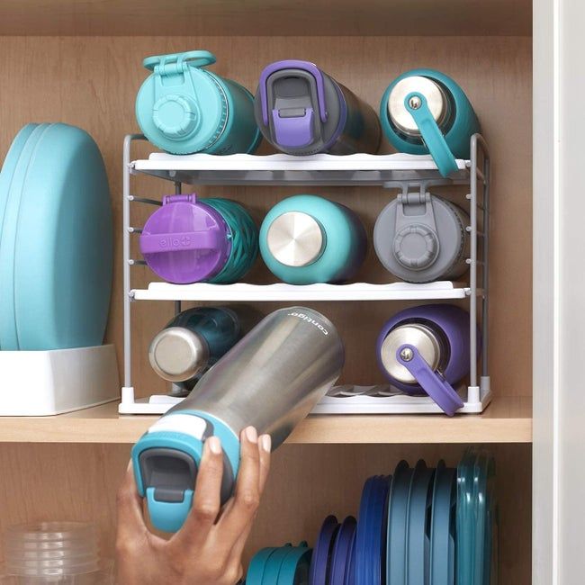 A model placing a water bottle on a storage rack inside a cabinet.