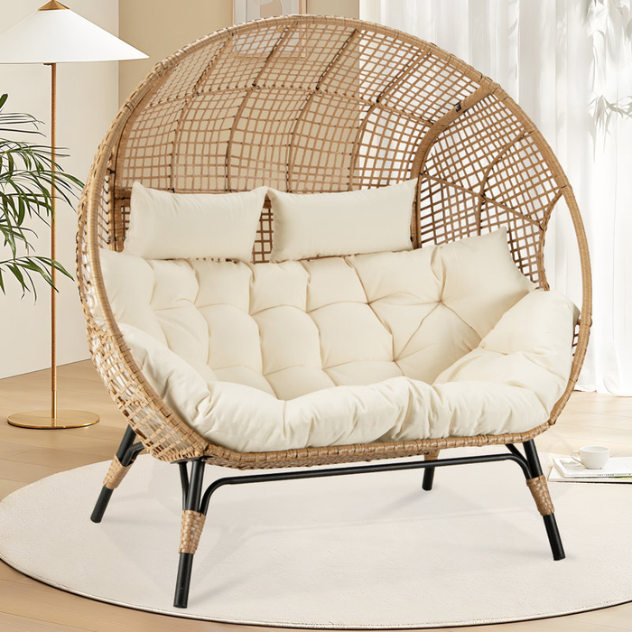 A round wicker lounge chair with plush cushions resting on a white rug in an indoor space.