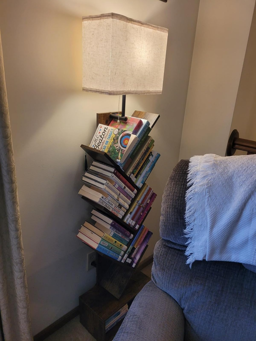 A lamp with an integrated bookshelf, holding a selection of books, set in a cozy living room environment