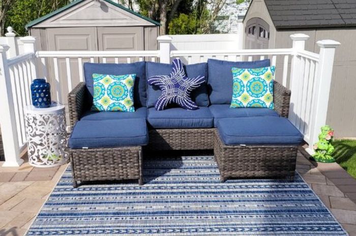Reviewer photo of a navy blue outdoor sofa with a starfish pillow and a rug, placed on a deck.
