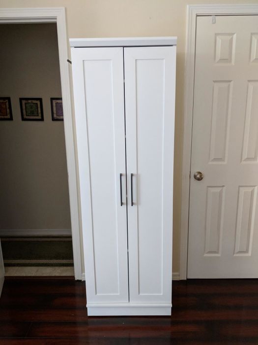 A reviewer's photo showing a slim white storage closet against a wall with its doors closed