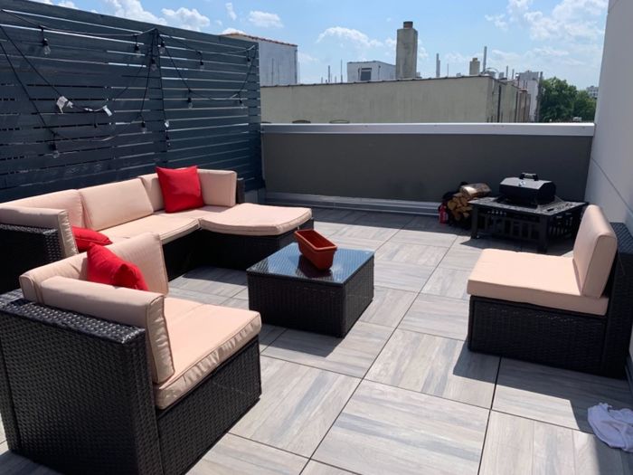 Reviewer photo showing a disassembled sectional with cream cushions spread across an outdoor rooftop.