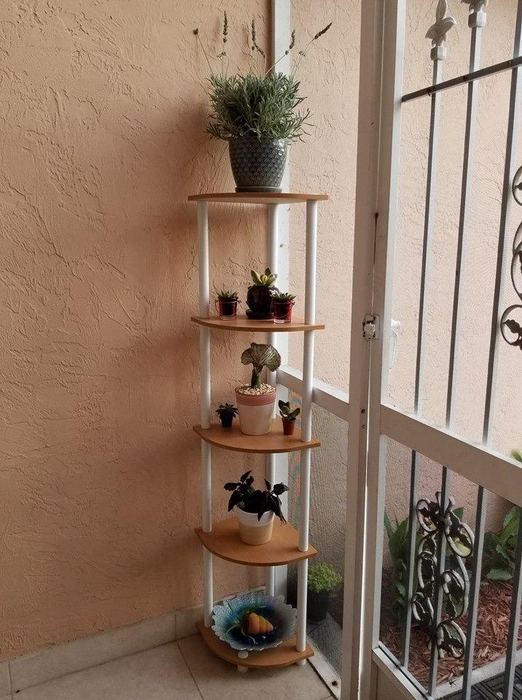 A reviewer image of a brown and white tiered corner bookshelf, each shelf holding a plant