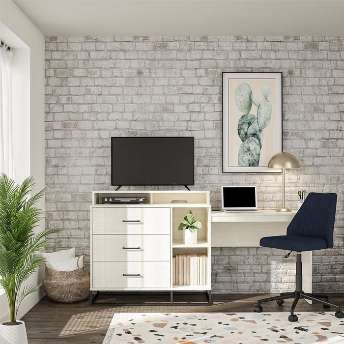 off-white dresser with three textured drawers, shelves, a TV on top, and a desk on the side