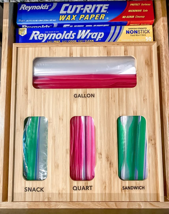 A kitchen drawer organizer filled with assorted sizes of plastic bags and foil, featuring separate sections for gallon, quart, sandwich, and snack bags.