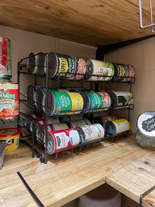 A reviewer's can organizer on a shelf, holding a variety of food cans to optimize pantry space.