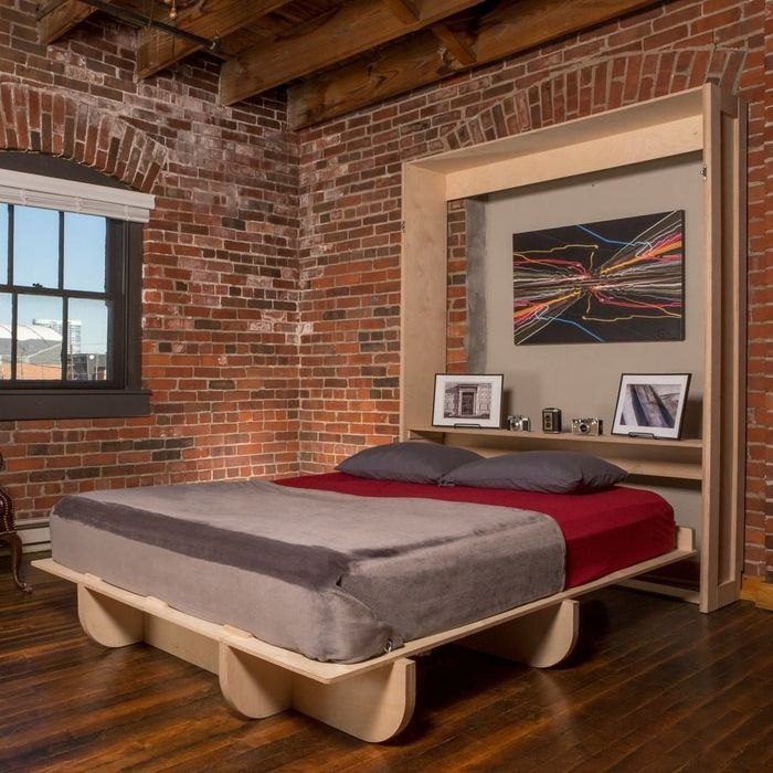 A Murphy bed with photos and artwork displayed on the shelf above