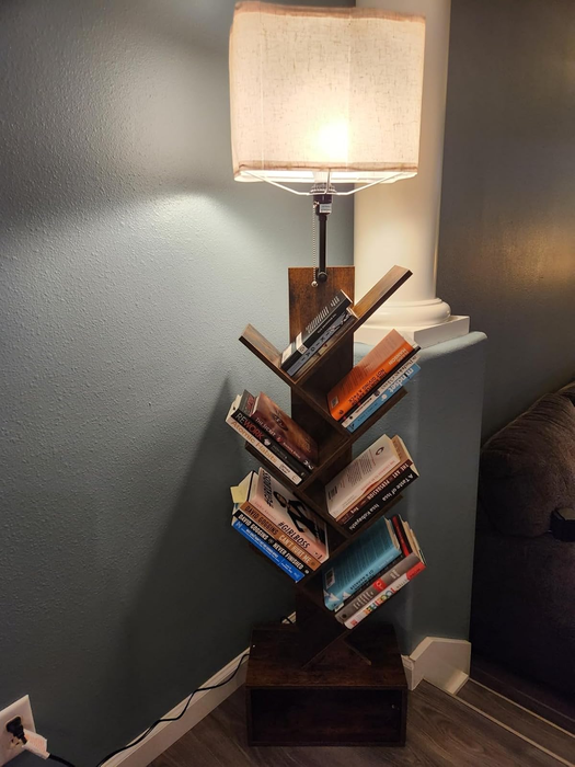 A lamp-style bookshelf with books neatly arranged on its tree-like shelves, blending lighting and storage into a modern decor piece