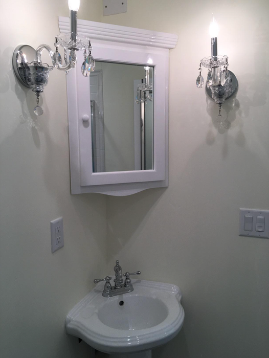 Image of a compact white corner cabinet featuring a mirror