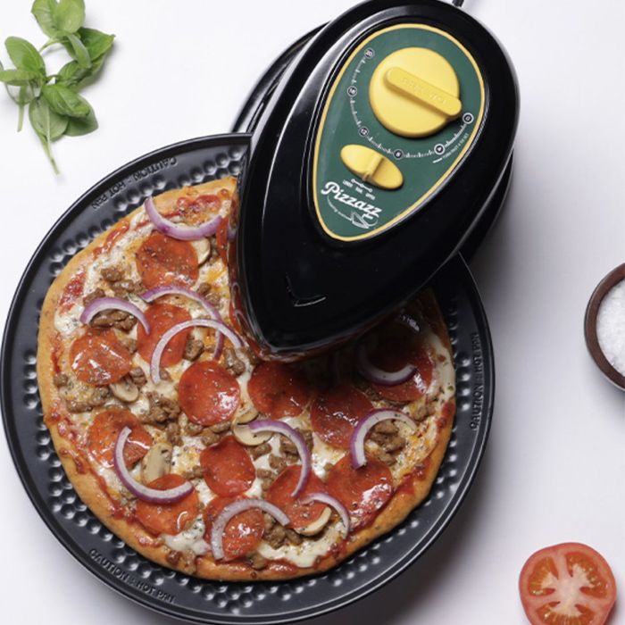 Pizza maker appliance on the kitchen countertop, with a freshly cooked pizza topped with pepperoni and onions, surrounded by fresh ingredients