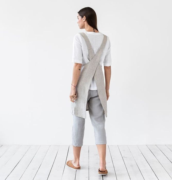 Back view of a model wearing the gray apron, highlighting its cross-back design
