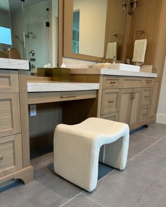 A contemporary bathroom vanity featuring a textured stool, wooden cabinets, and a single sink setup.