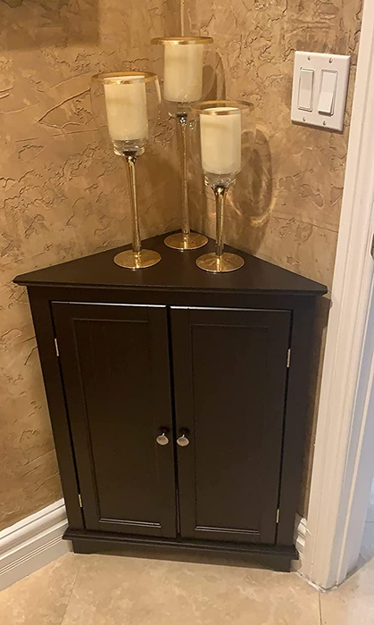 Image of a compact dark brown corner cabinet adorned with candles on top