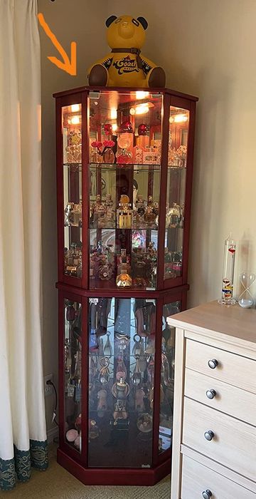Image of a cherry wooden corner cabinet with mirrored panels, placed next to a dresser