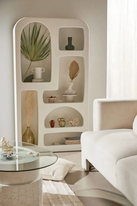 An abstract bookshelf featuring shelves of various shapes and sizes, most with soft curves. Some are arranged vertically, while others are horizontal.