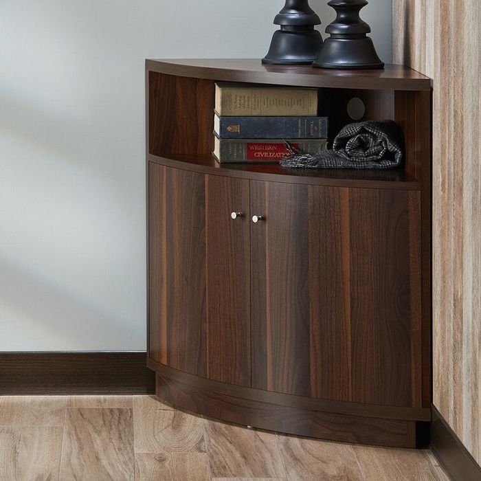 A dark wooden corner cabinet with two doors and a small top shelf