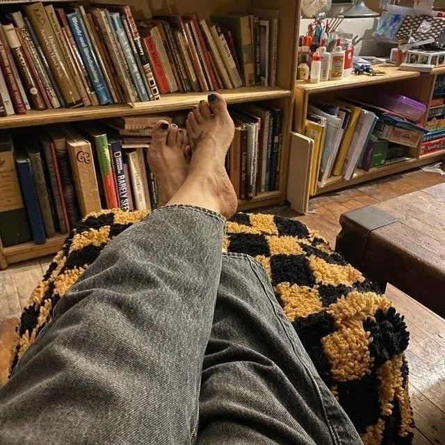 A yellow and black pouf placed in a living room.