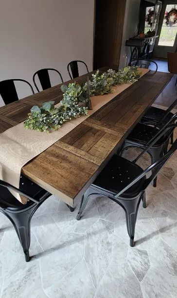 A table set with metal chairs, featuring a burlap centerpiece adorned with green flowers.