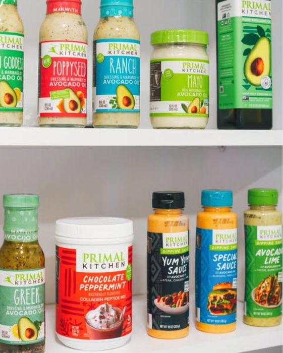 A variety of Primal Kitchen sauces, dressings, and mixes neatly arranged on a pantry shelf, showcasing options like ranch, poppyseed, and avocado mayo