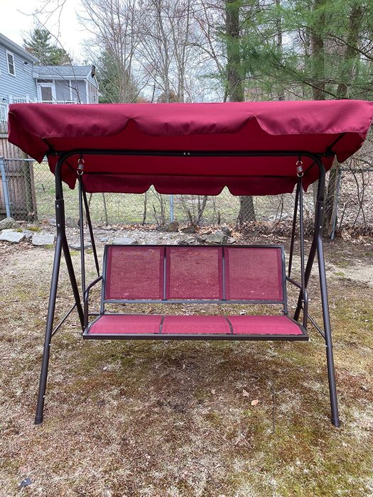A reviewer’s photo of their red glider swing on the porch.