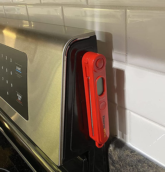 A reviewer's photo of the magnetic food thermometer attached to the side of a stove
