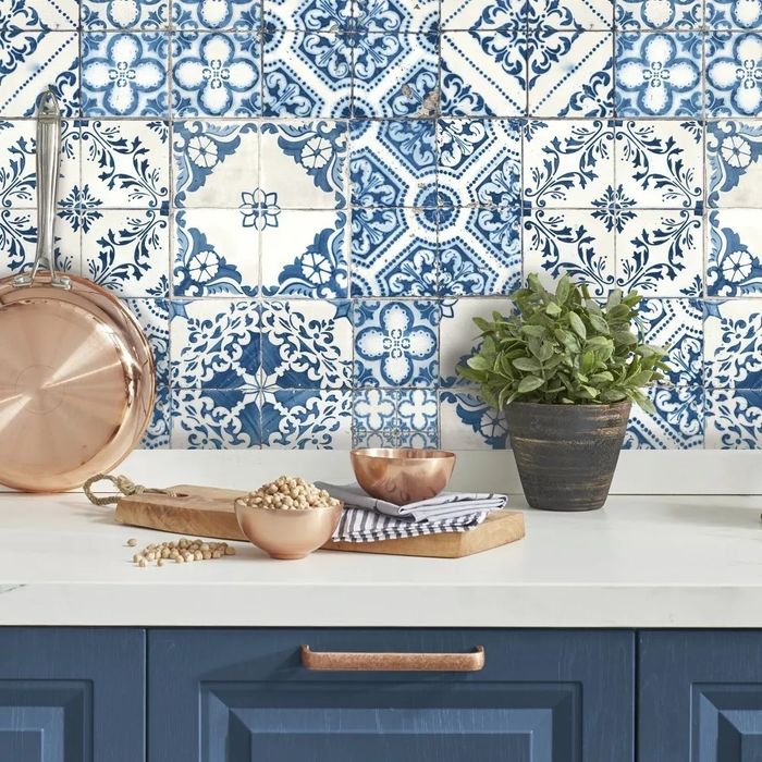 A kitchen counter adorned with patterned tiles, copper cookware, chickpeas in a bowl, a striped cloth, and a potted plant for a cozy, inviting feel.