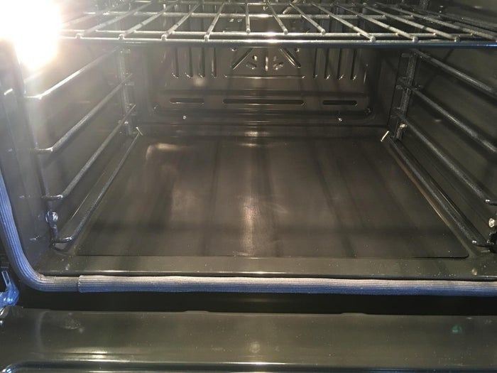 An open, empty oven with light streaming in, showcasing the pristine, clean interior and racks