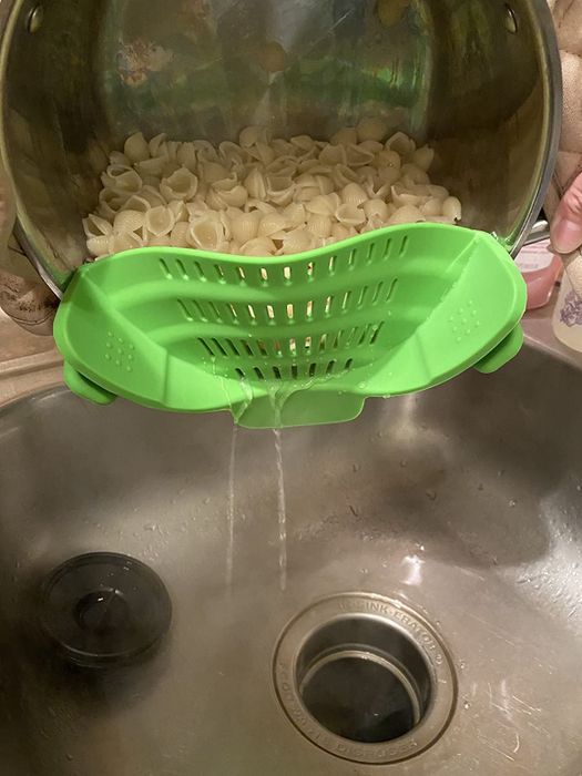 Reviewer image of the strainer attached to a pot draining water from pasta