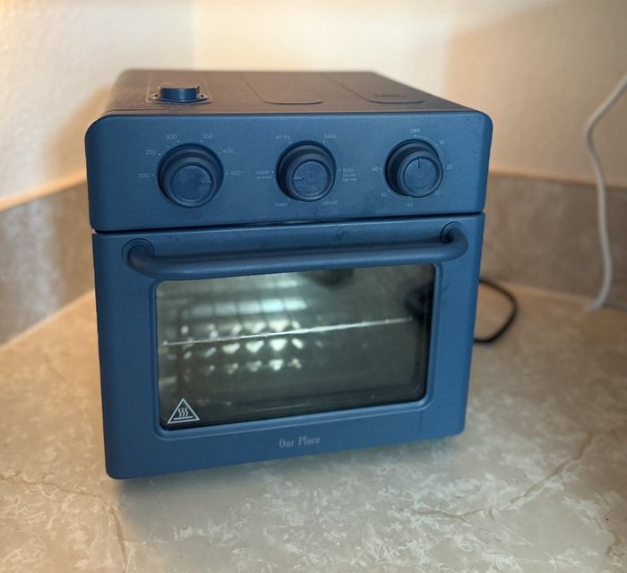 Countertop oven with three dials and a glass door placed on a kitchen counter