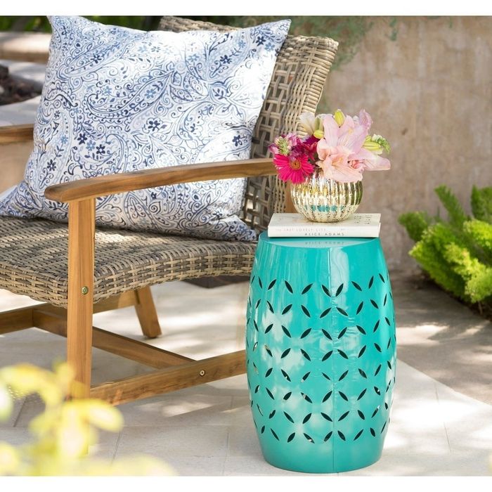 A teal side table placed outdoors next to a patio chair.