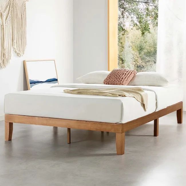 A wooden bed frame with a mattress and blanket neatly arranged on top.