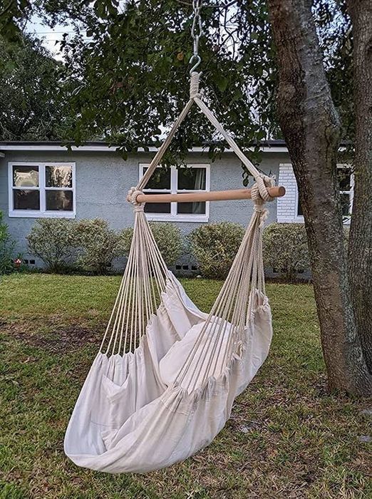 A reviewer's image showing an off-white hammock chair hanging from a tree in their yard.