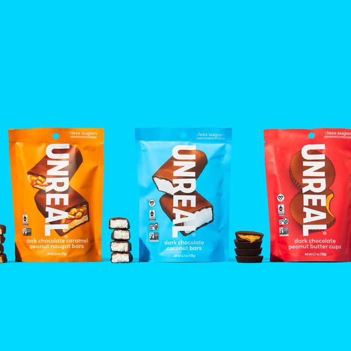 Three bags of Unreal chocolate treats: peanut nougat, coconut bars, and peanut butter cups, with their contents displayed in front of them