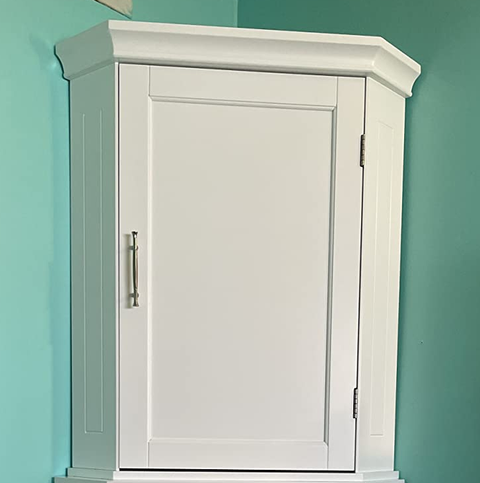 Image of a compact corner cabinet placed against a teal wall