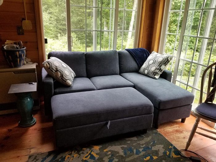 A photo from a reviewer showing the bluish-gray sectional sofa with the ottoman pushed in to transform it into a sleeper.