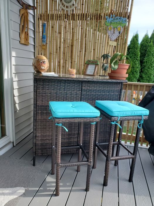 A reviewer's photo of the outdoor bar set featuring blue cushions.