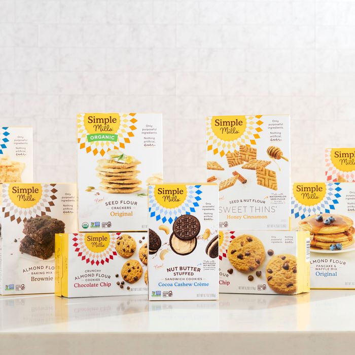 A variety of Simple Mills snacks, including cookies and crackers, neatly arranged on a kitchen countertop
